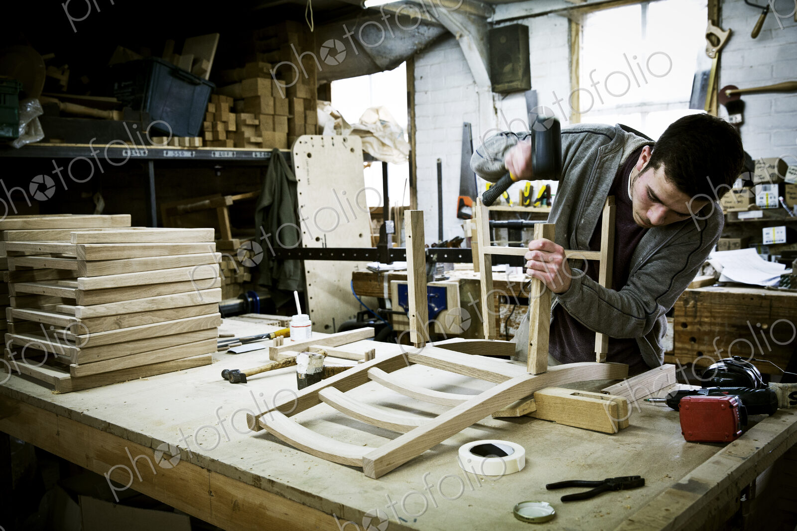 A man working in a furniture maker’s workshop assembling a chair.