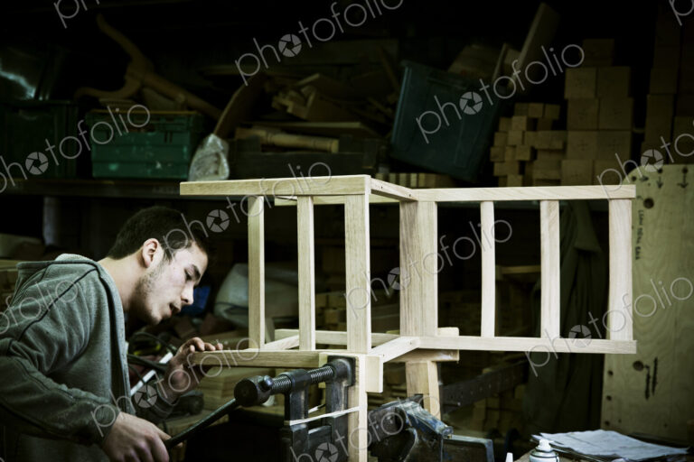 A man working in a furniture maker's workshop assembling a chair.