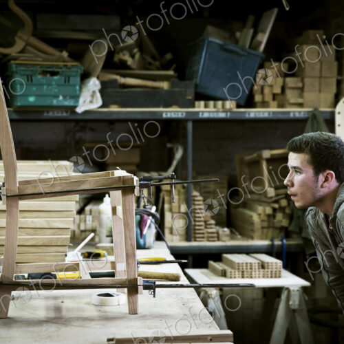 A man working in a furniture maker's workshop assembling a chair.