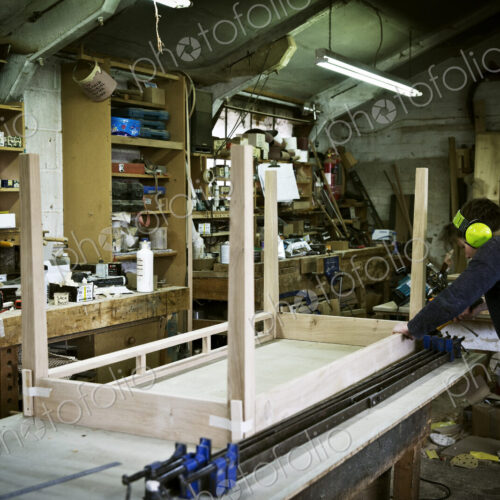 A man working in a furniture maker's workshop, assembling a table. A man working in a furniture maker's workshop, assembling a table.