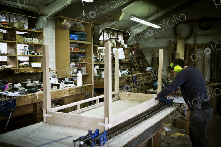 A man working in a furniture maker's workshop, assembling a table.