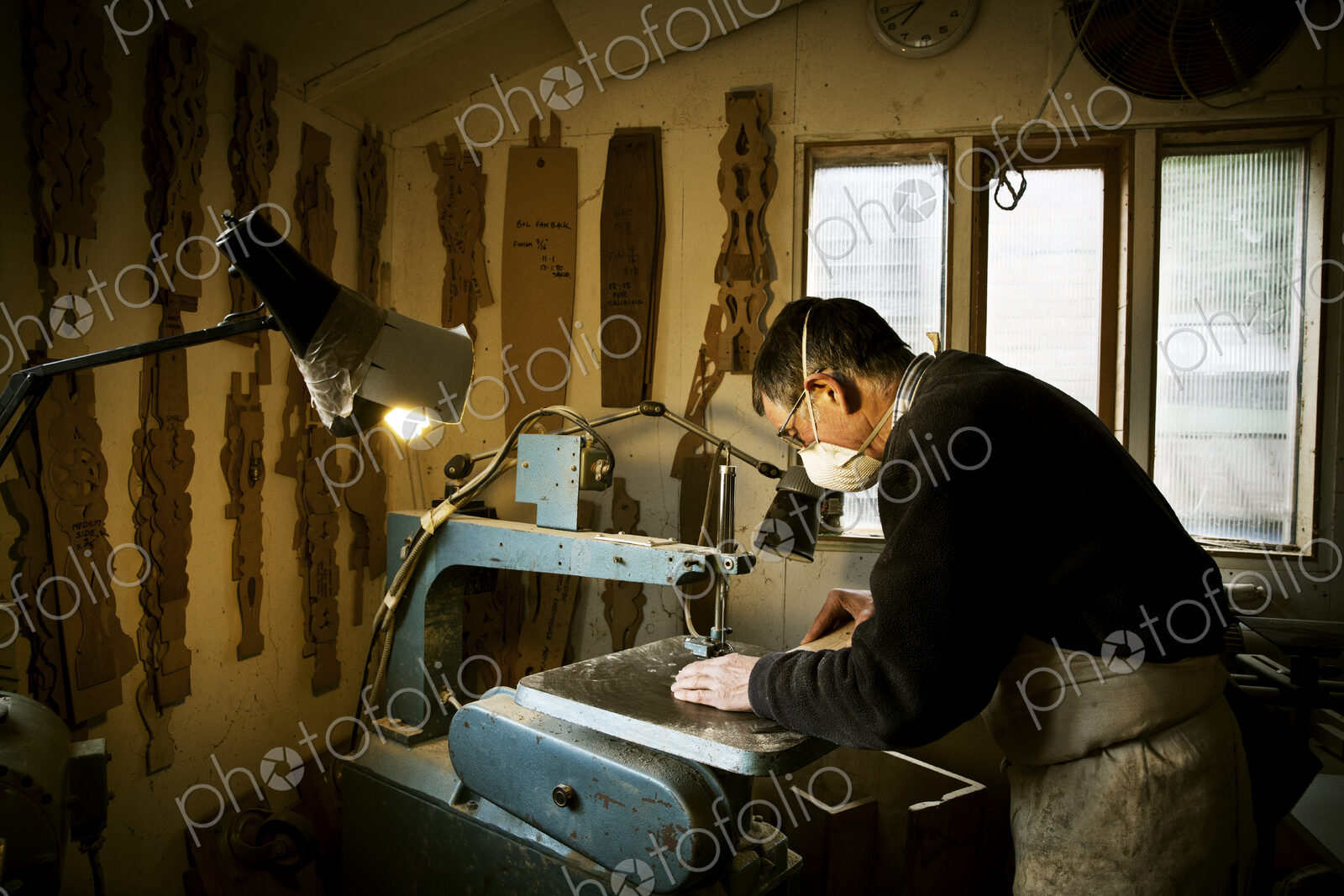 A man working in a furniture maker’s workshop, using a machine saw.