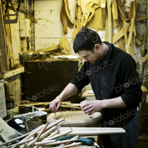 A man working in a furniture maker's workshop. Chairlegs on the bench.