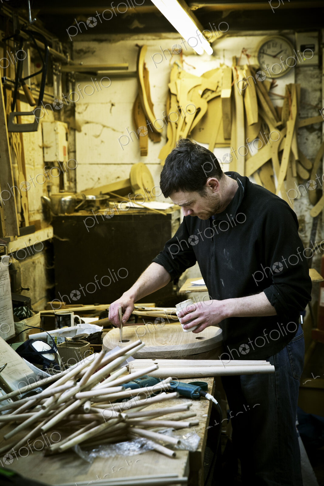 A man working in a furniture maker’s workshop. Chairlegs on the bench.