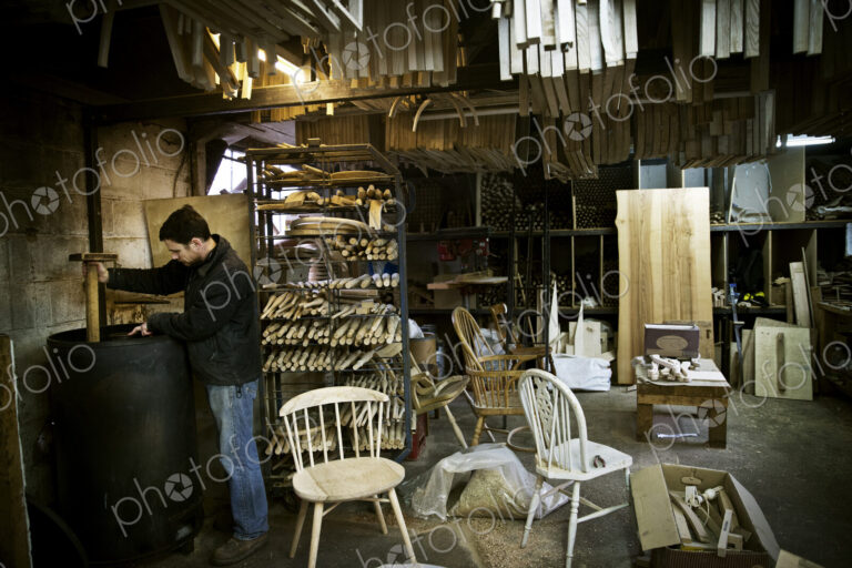A man working in a furniture maker's workshop. Windsor chairs.
