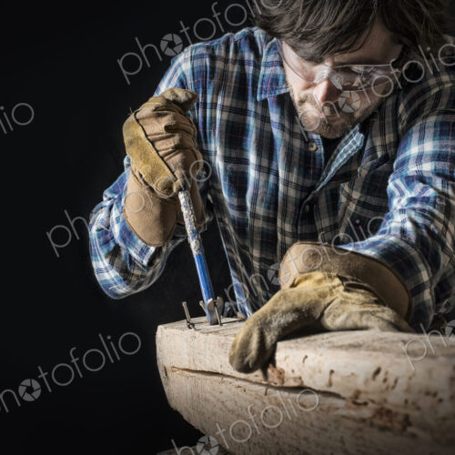 A man working in a reclaimed lumber yard workshop. Holding tools and extracting nails…