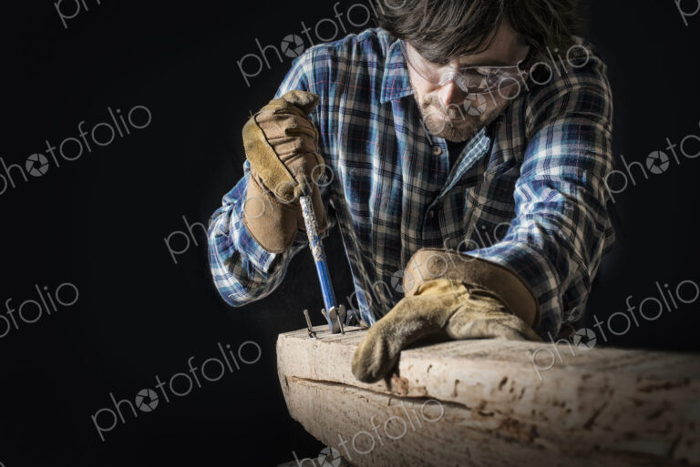 A man working in a reclaimed lumber yard workshop. Holding tools and extracting nails…