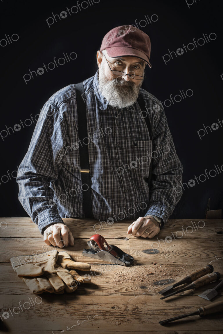 A man working in a reclaimed lumber yard workshop. Holding tools and working on a…