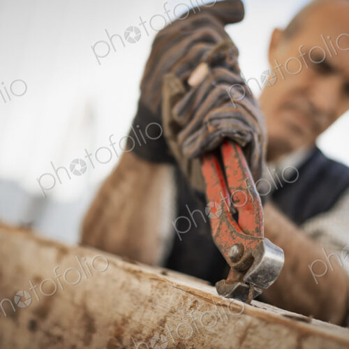 A man working in a reclaimed timber yard. Using a tool to remove metals from a… A man working in a reclaimed timber yard. Using a tool to remove metals from a…