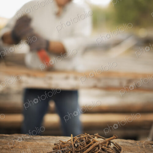 A man working in a reclaimed timber yard. Using a tool to remove metals from a… A man working in a reclaimed timber yard. Using a tool to remove metals from a…