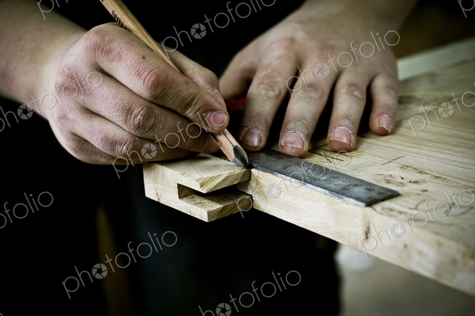 A man working on wood, measuring a joint or corner with a ruler and pencil.