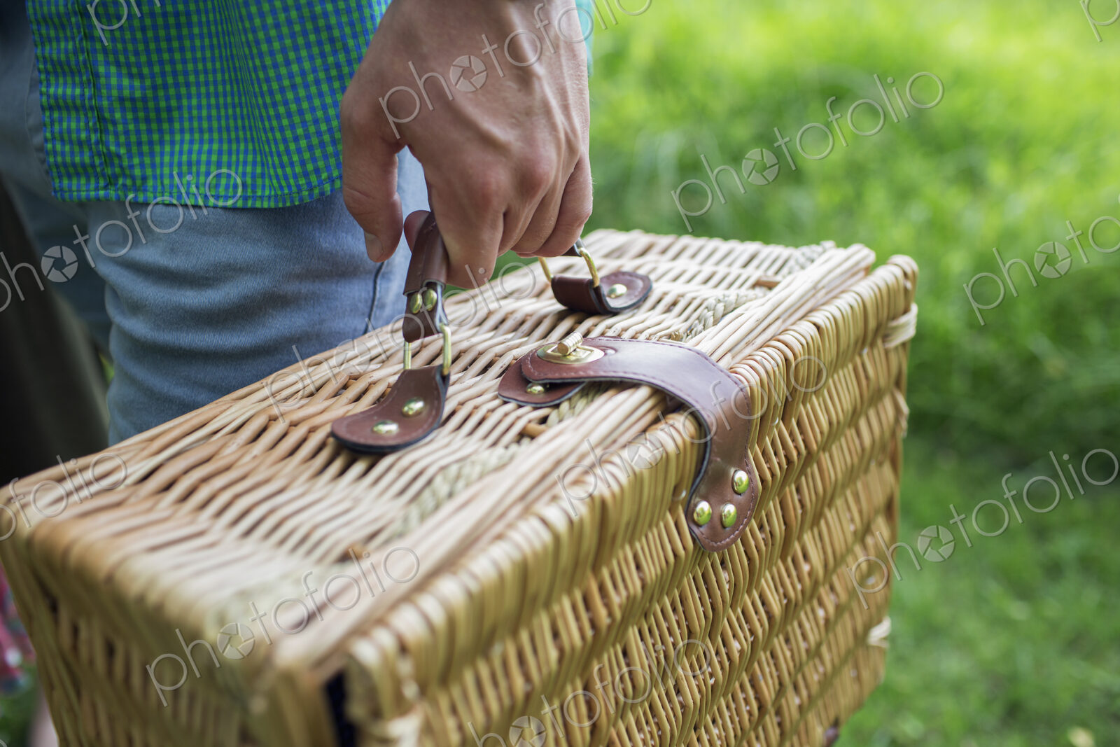 A man’s hand holding a wicker picnic basket.