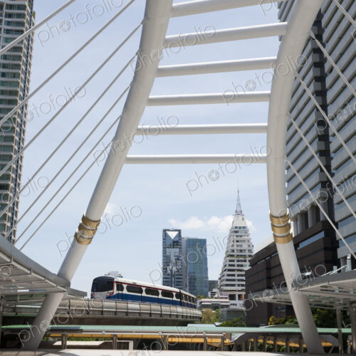 A mass transit train on an elevated track passes modern buildings in the central… A mass transit train on an elevated track passes modern buildings in the central…