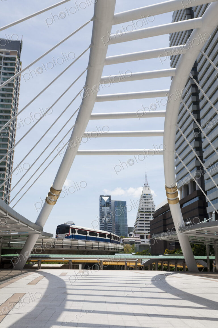 A mass transit train on an elevated track passes modern buildings in the central…