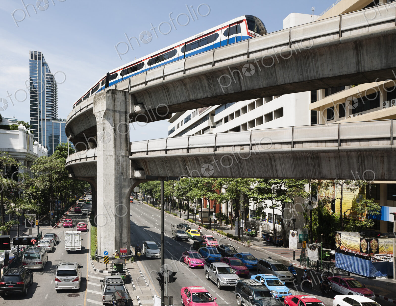 A mass transit train travelling on an elevated track above a busy city road in Bangkok.