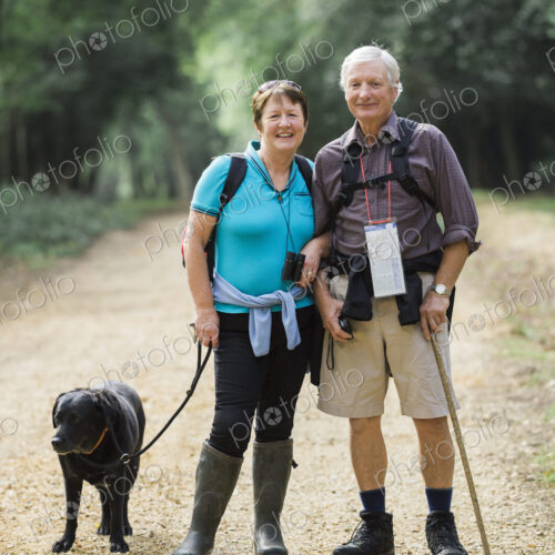 A mature couple hiking with their dog.