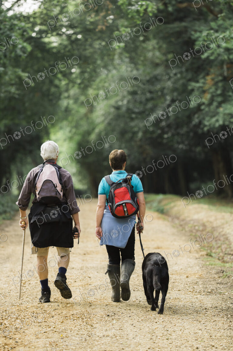A mature couple hiking with their dog.