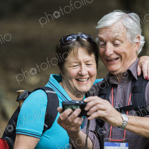 A mature couple looking at a digital camera, laughing. A mature couple looking at a digital camera, laughing.