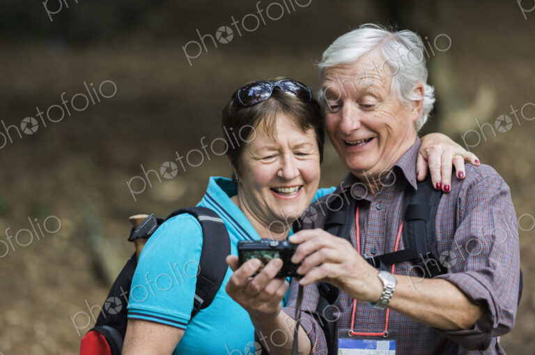 A mature couple looking at a digital camera, laughing.