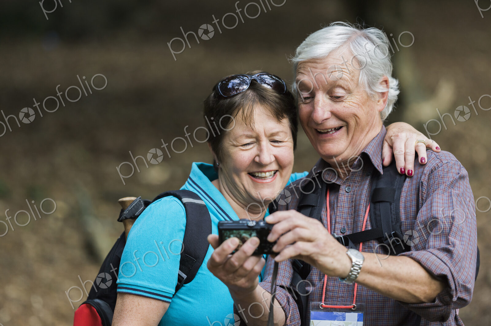 A mature couple looking at a digital camera, laughing.