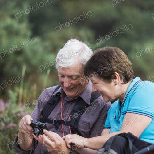 A mature couple taking photographs while out walking.