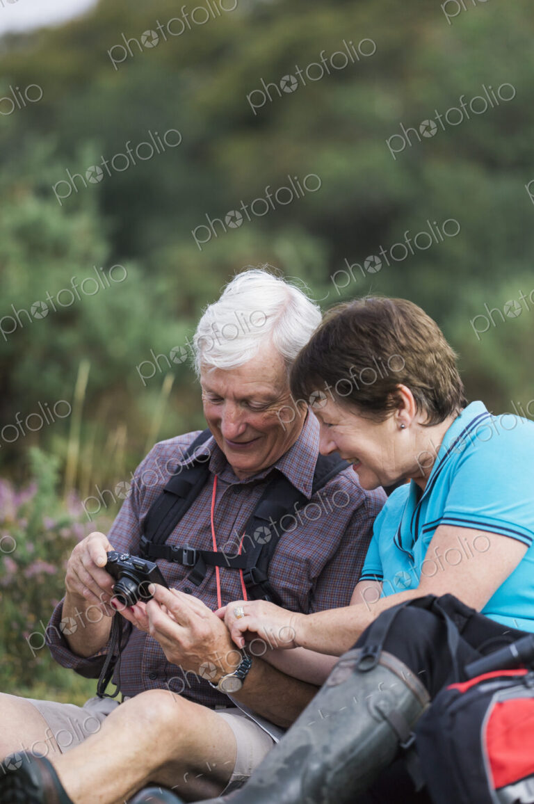 A mature couple taking photographs while out walking.