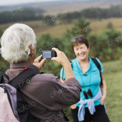 A mature couple taking photographs while out walking. A mature couple taking photographs while out walking.
