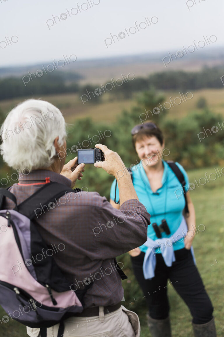 A mature couple taking photographs while out walking.
