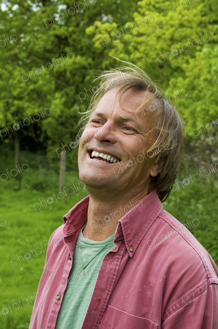 A mature man in casual clothes with blonde hair, smiling broadly.