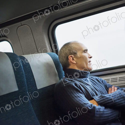 A mature man sitting in a window seat on a train journey, looking out into the distance. A mature man sitting in a window seat on a train journey, looking out into the distance.