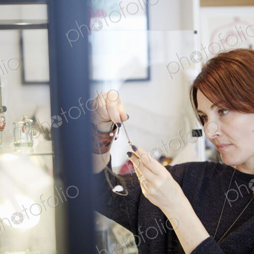 A mature woman holding a piece of jewellery in a shop