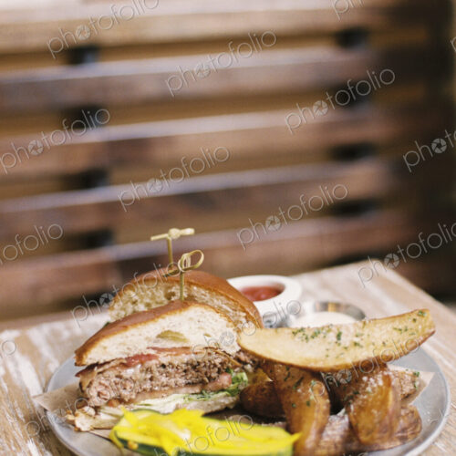 A meal, a hamburger in a bun, potato fries and a gherkin. A meal, a hamburger in a bun, potato fries and a gherkin.