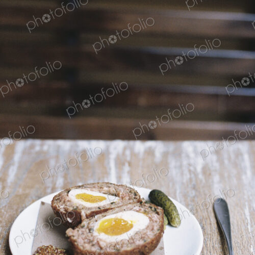 A meal on a plate, a scotch egg cut in half with garnishes. A meal on a plate, a scotch egg cut in half with garnishes.