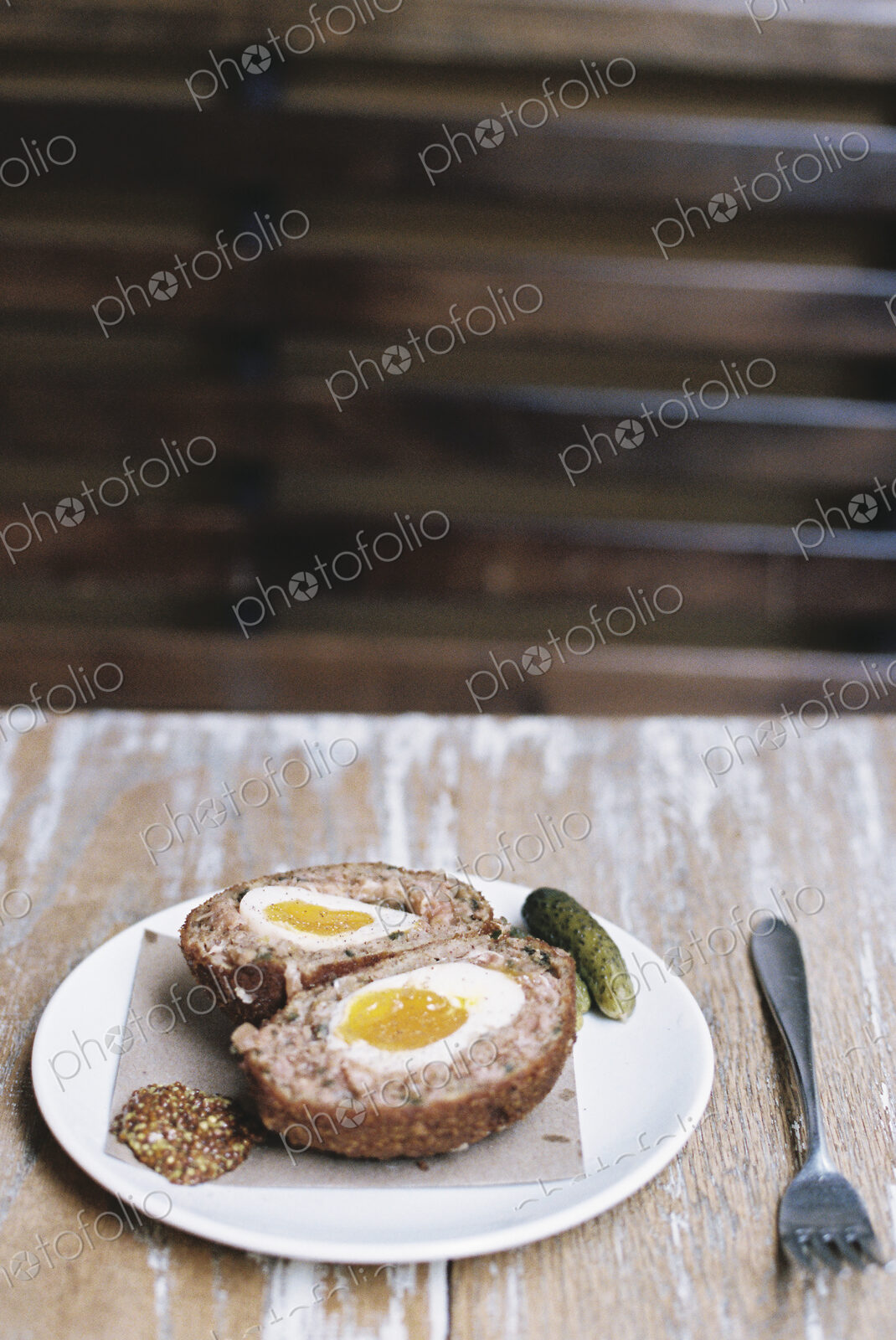 A meal on a plate, a scotch egg cut in half with garnishes.