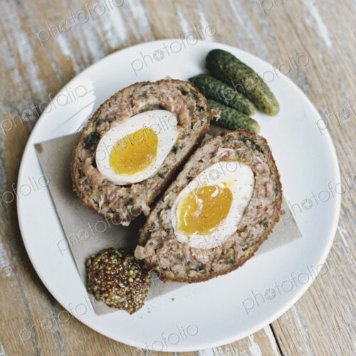 A meal on a plate, a scotch egg cut in half with garnishes. A meal on a plate, a scotch egg cut in half with garnishes.