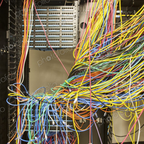 A mess of Cat 5 cables in an office server room. A mess of Cat 5 cables in an office server room.
