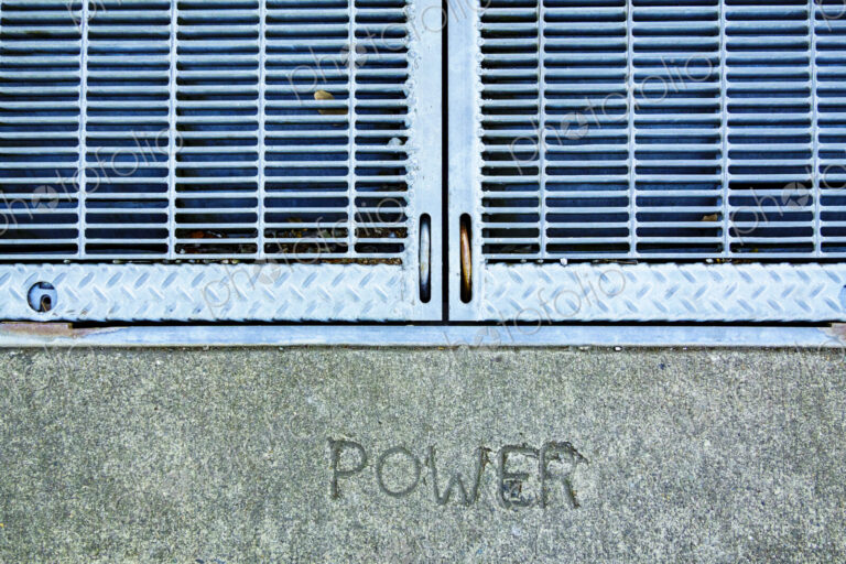 A metal grille over a power utility vault on a wall, the word Power embossed in stone.