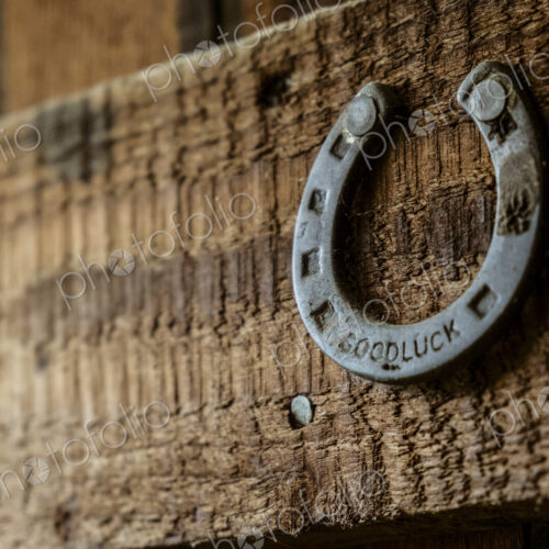A metal horseshoe nailed onto a wooden beam.