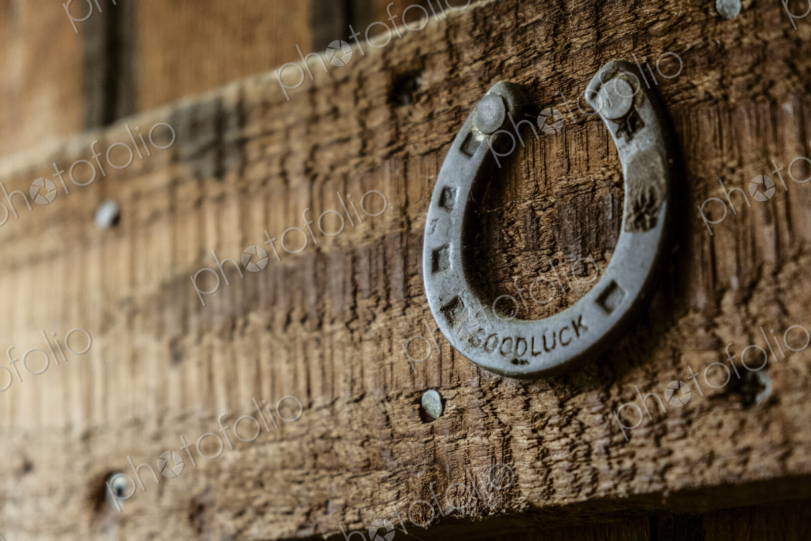 A metal horseshoe nailed onto a wooden beam.