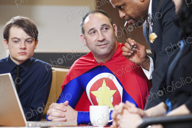 A middle aged caucasian office super hero in a meeting with his staff.