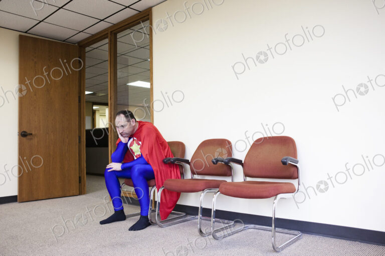 A middle aged caucasisan office super hero ponders the stress of the job.