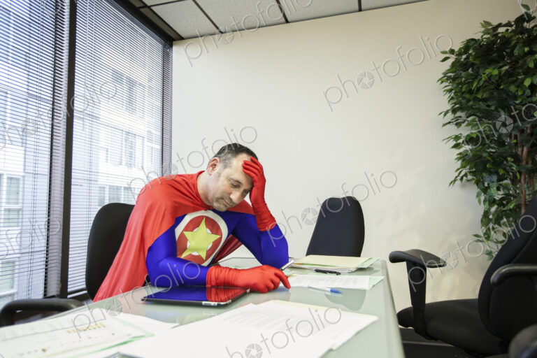 A middle aged caucasisan office super hero ponders the stress of the job.