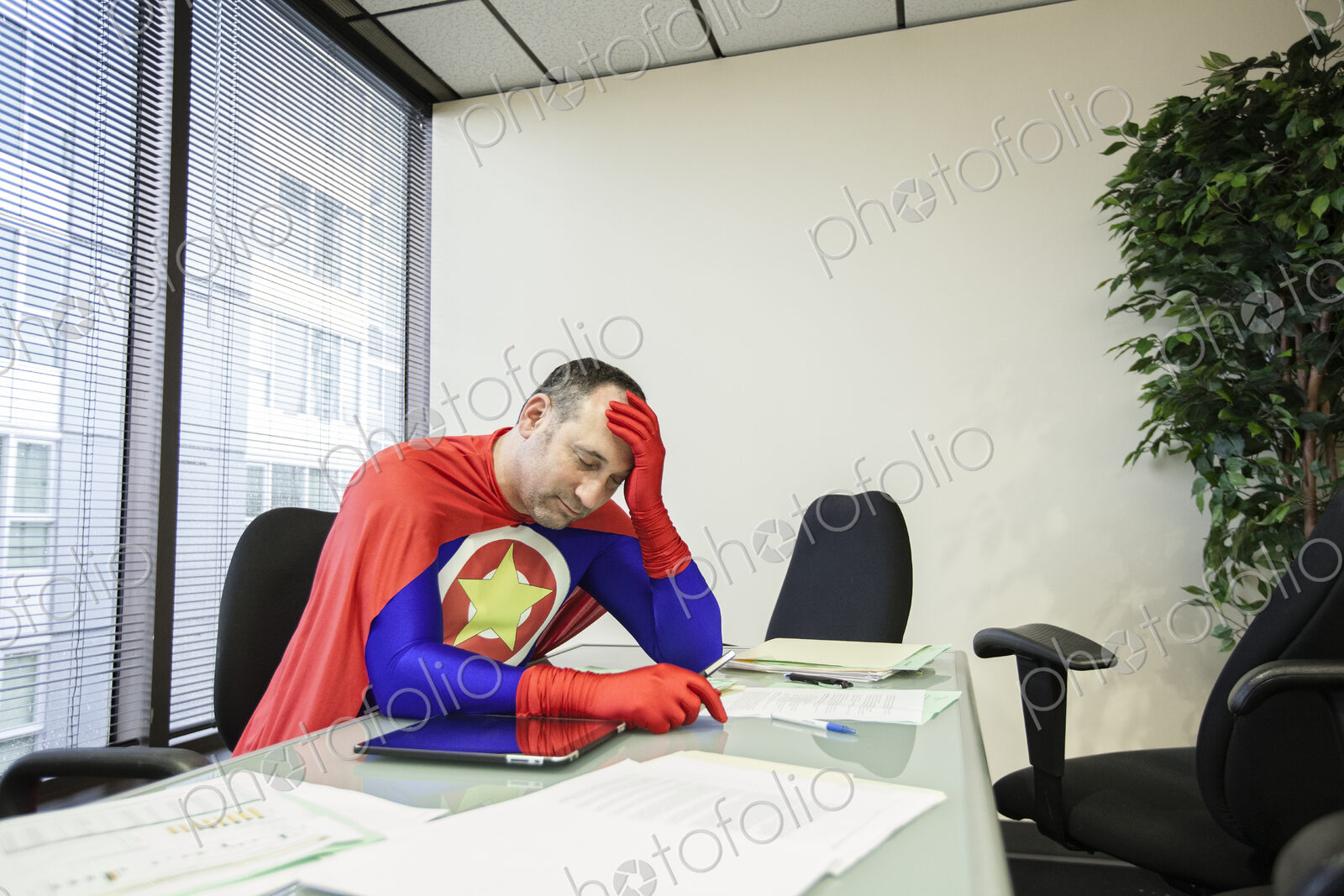 A middle aged caucasian office super hero ponders the stress of the job.