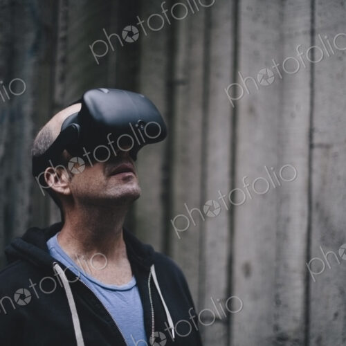 A middle aged man wearing a virtual reality headset. A middle aged man wearing a virtual reality headset.