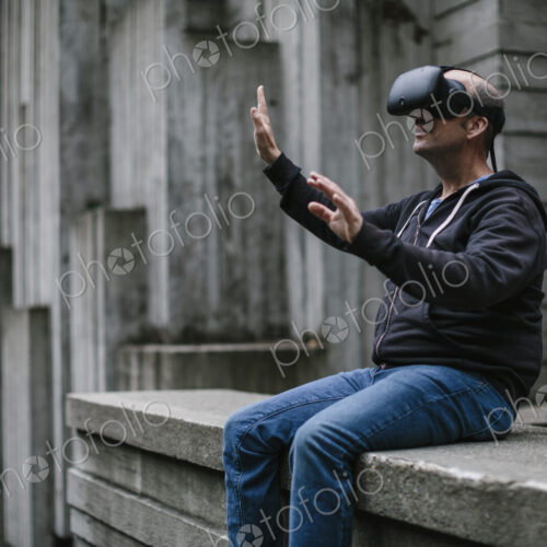 A middle aged man wearing a virtual reality headset. A middle aged man wearing a virtual reality headset.