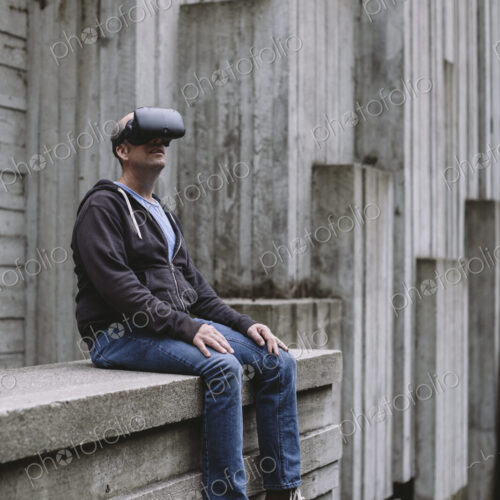 A middle aged man wearing a virtual reality headset. A middle aged man wearing a virtual reality headset.