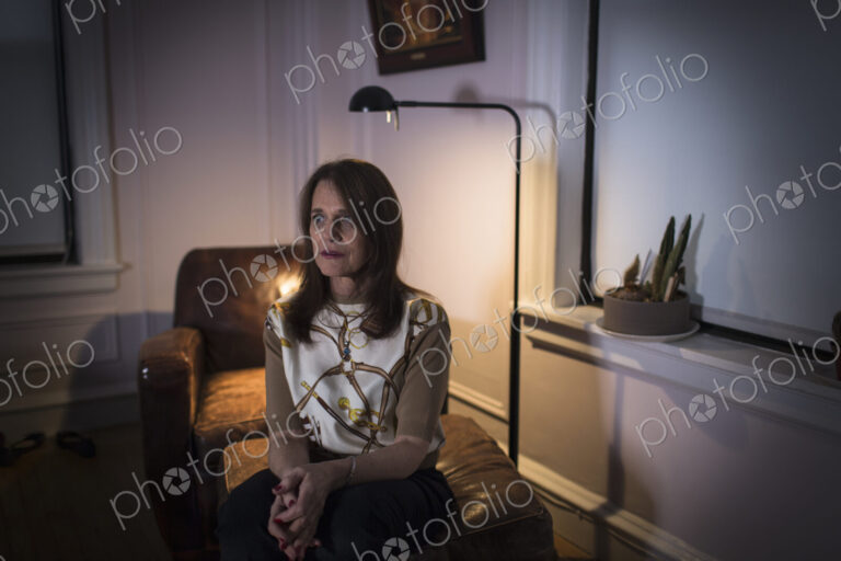 A middle aged woman seated with a sad expression.