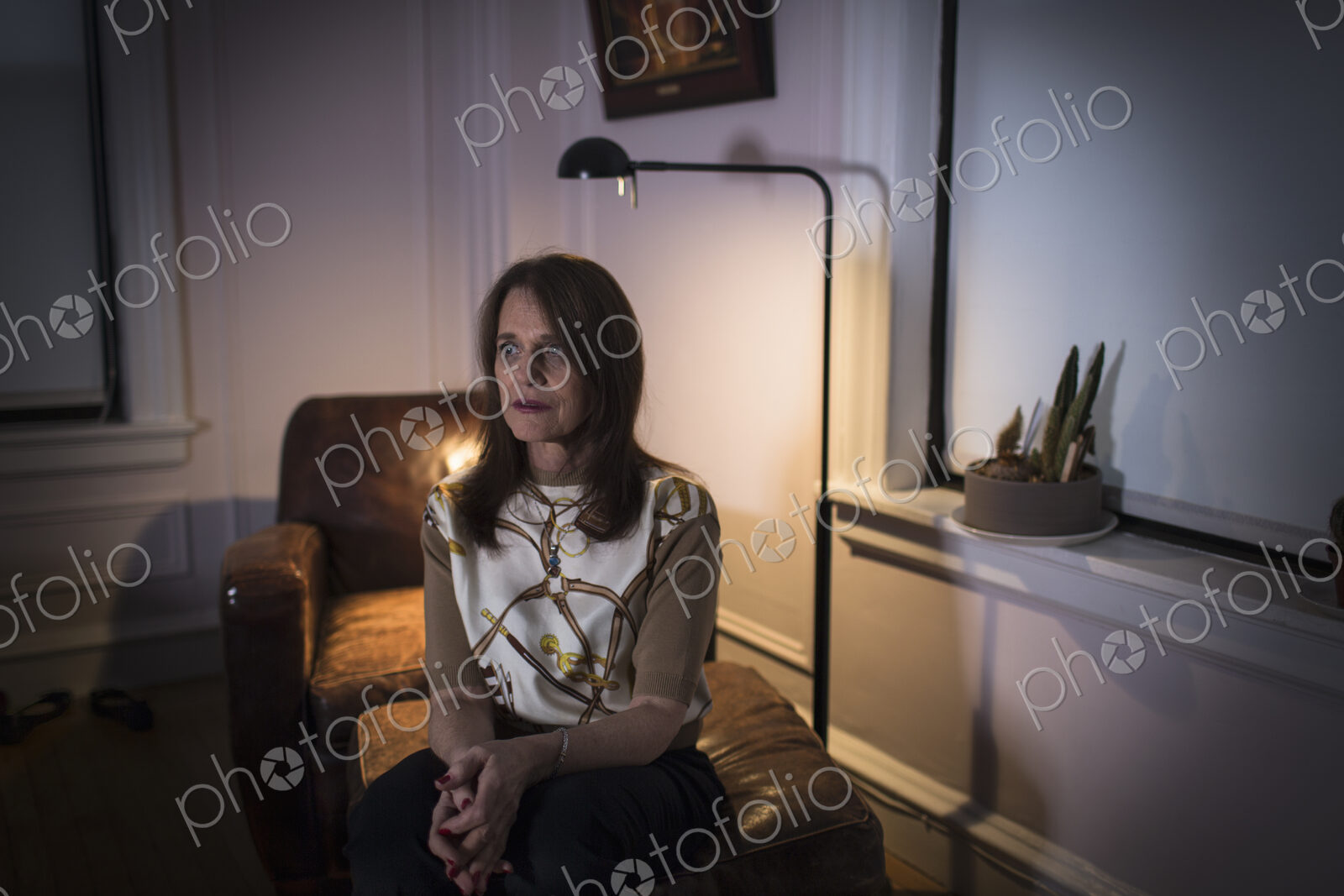 A middle aged woman seated with a sad expression.