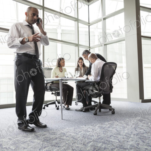 A middle eastern businessman on the phone during a meeting.