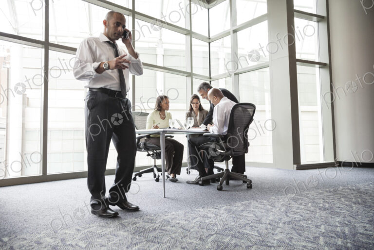 A middle eastern businessman on the phone during a meeting.